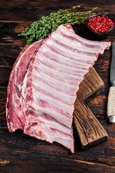 Mutton lamb ribs rack on wooden cutting board. Dark wooden background. Top view