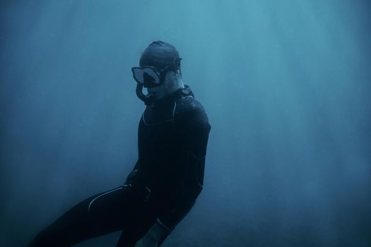 Man diver in wetsuit swimming underwater.