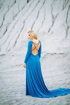 blonde girl in a blue dress with blue eyes in a granite quarry