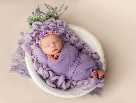 Newborn sleeping wrapped in violet blanket