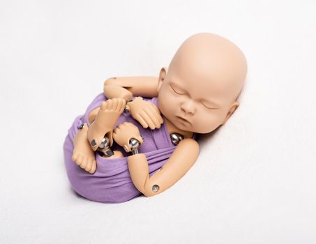Doll of newborn kid in sling