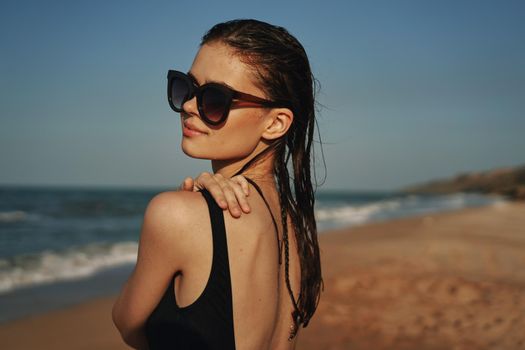 cheerful woman in black swimsuit sunglasses beach walk travel. High quality photo