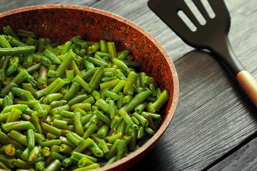 Vegetarian food. Fried string beans in a pan. Stylish background for design. Minimalism. Healthy food from vegetables.