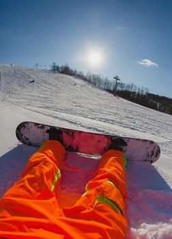 Point of view shot of a male snowboarder sitting on the snow