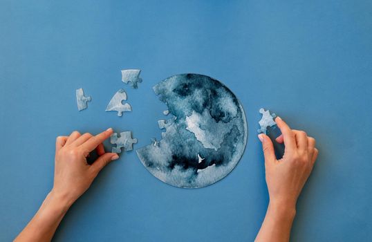 Hands collecting round jigsaw puzzle