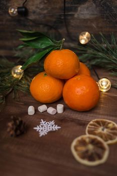 Christmas still life with fresh mandarines, marshmallows and snowflake on wooden background
