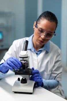 Biologist doctor putting blood sample under medical microscope