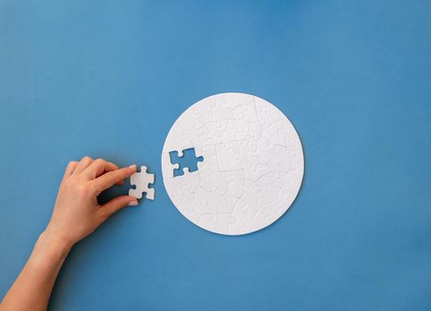 Hand putting piece in round puzzle
