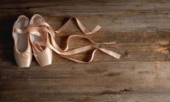 Pointe shoes with ribbons on wooden background