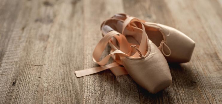 Pointe shoes with ribbons on wooden background