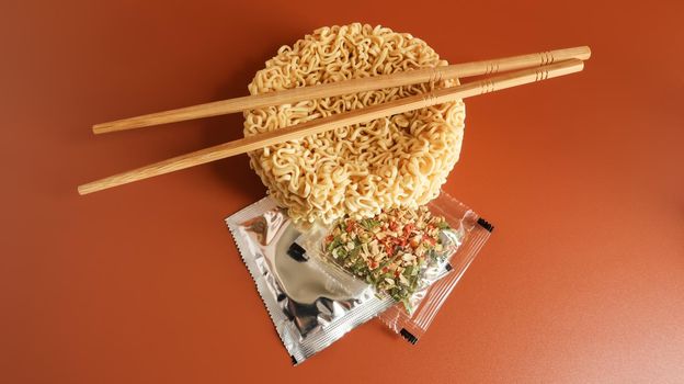 Raw instant noodles with chopsticks and spices. Copy space asian food. pasta, for the preparation of which it is enough to pour boiling water and wait a few minutes. flavored spaghetti.