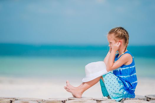 Little girl listening to music on headphones on caribbean beach
