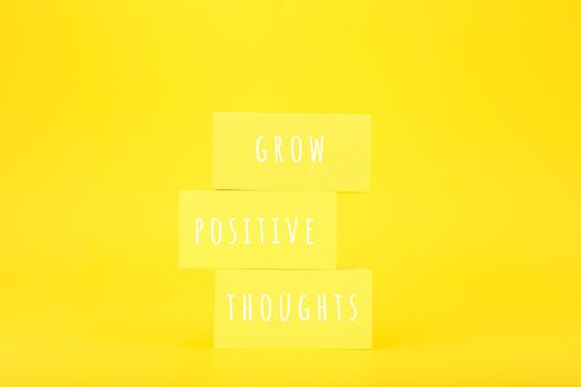 Positive affirmation or motivational quote concept. Grow positive thoughts written on yellow rectangles on yellow background