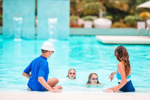 Young family with two kids enjoy summer vacation in outdoor pool