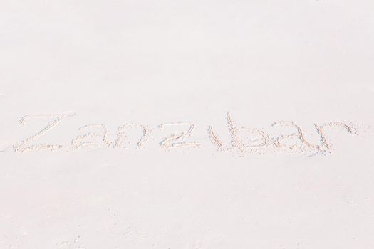 Word handwritten on sandy beach with soft ocean wave on background