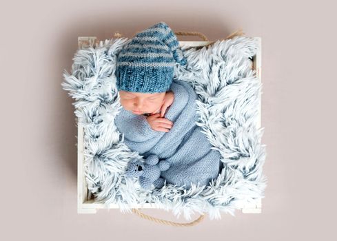 Newborn infant sleeping in box among blue blankets