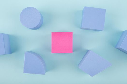 Concept of individuality and being different from others in blue colors. Pink cube and blue geometric figures on bright background