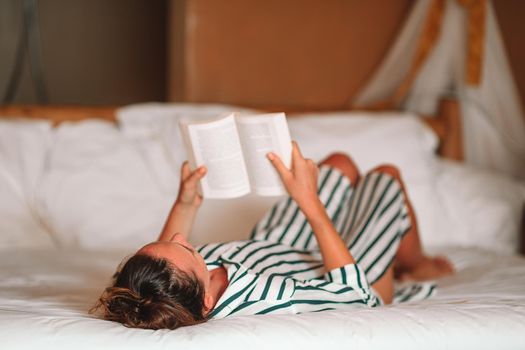 Beautiful woman reading book in bed relaxing
