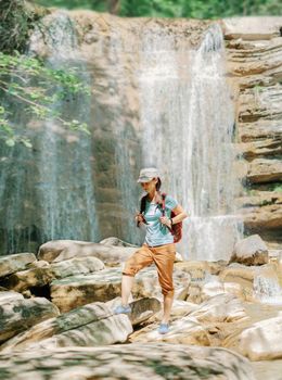 Explorer woman walking in front of waterfall.