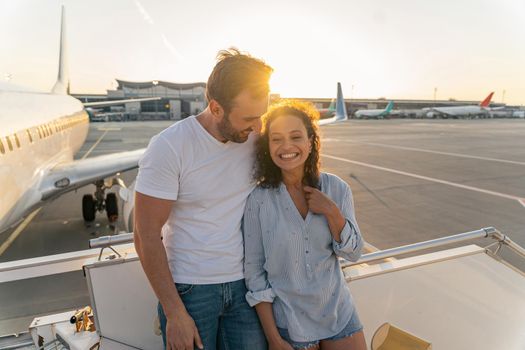 Couple in love standing on the plane ladder before the flight
