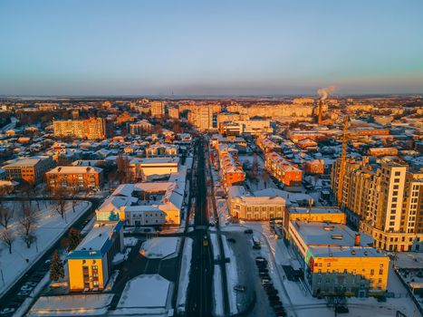 Aerial view of road in small european city with snow covered roofs at winter sunset
