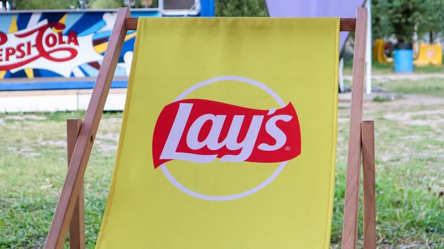 Yellow chairs in a cafe with the Lais logo in the summer. Urban marketing branding. a brand of potato chips produced since 1938. Since 1965 it is owned by PepsiCo.Ukraine, Kyiv - September 6, 2020.