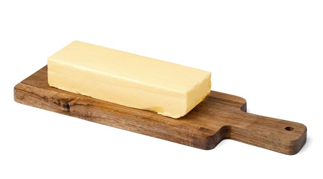 Butter on wooden board isolated on white background