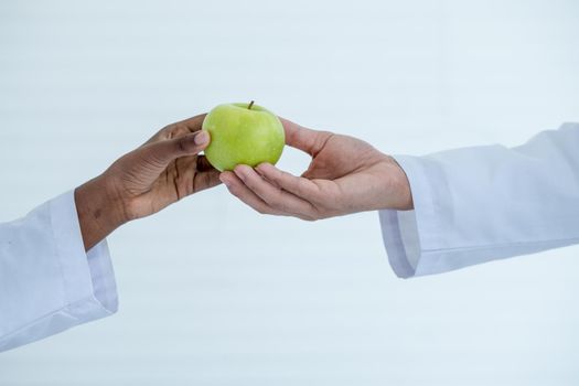 Close up hand of black of African american student give green apple to white man hand for respect the teacher before or during study in school or classroom.