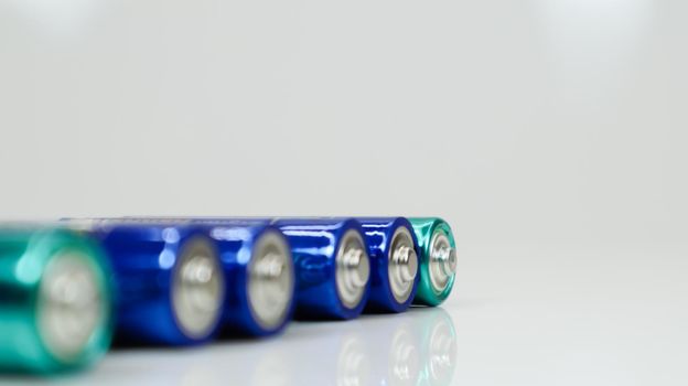 AA alkaline rechargeable batteries on white glossy background with reflection with copy space.