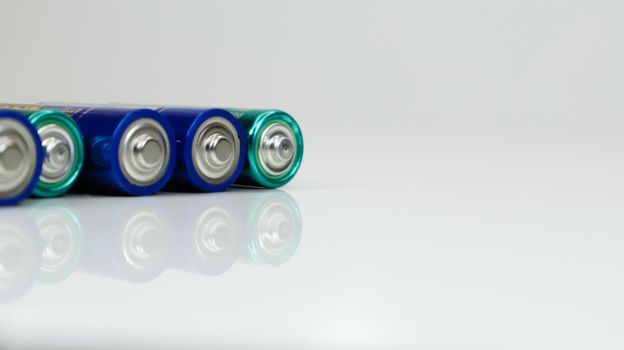 AA alkaline rechargeable batteries on white glossy background with reflection with copy space.