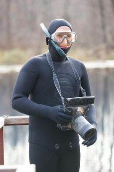 fisherman in wetsuit with photo camera in hands in preparation for a hunt