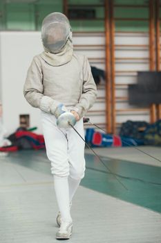 Young fencer in special costume at the fencing competition with rapier