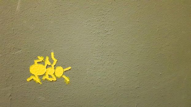 yellow painted ant on a gray wall. Ant climbing a wall. Colorful ants backgrounds. Local artists decorate the walls of the streets.