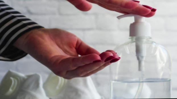 Close up of female hands washing their hands with alcohol gel. The girl presses on the dispenser and pours alcohol-based liquid. A disinfectant to eliminate bacteria and viruses. Covid-19.