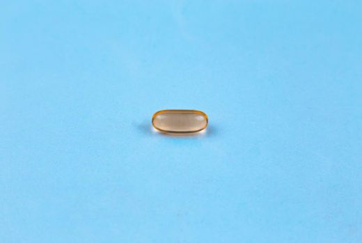 Fish oil supplement capsule isolated on blue background