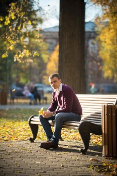 A man sitting on a bench in the autumn park
