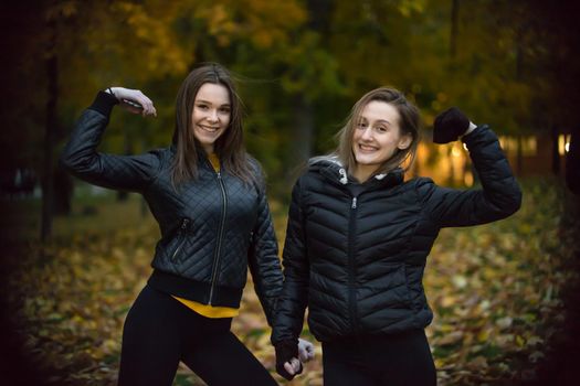 portrait of two girls in black jackets in autumn forest