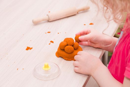 little girl plays with kinetic orange sand on a wooden light table. copy space