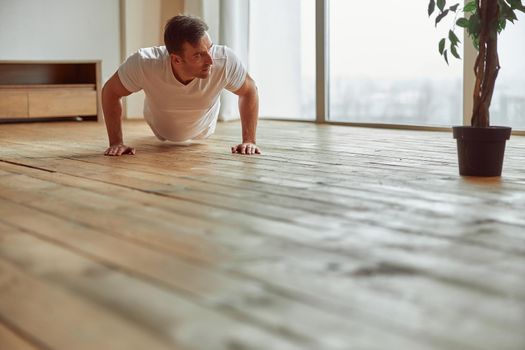 Strong man doing plank at home alone