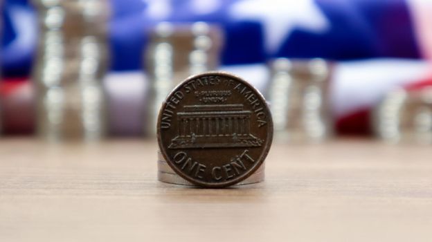 A 1 cent American dollar coin lies on the American flag. The currency is one cent over the flag of the United States.