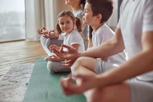 Happy little girl practicing meditation with family