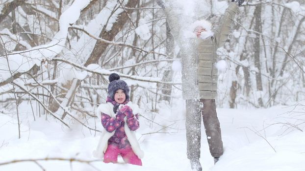 Two little girls playing with snow in winter forest.