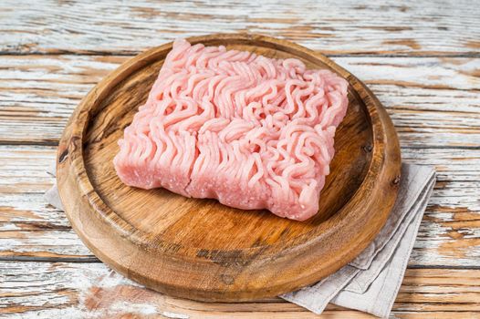 Raw mince or ground chicken meat on wooden board. White background. Top view