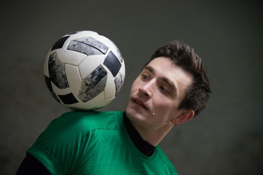 Football concept. Soccer player balancing a ball on his shoulder