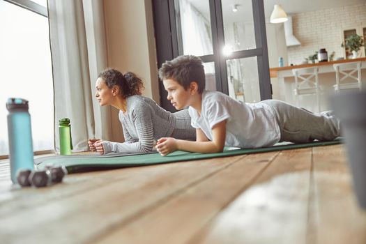 Sporty mom training core with son at home