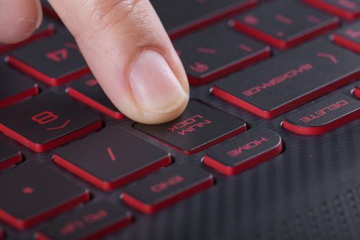 finger pushing num lock button on a laptop keyboard