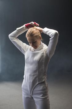 A young woman fencer putting her hair up into a bun before the training