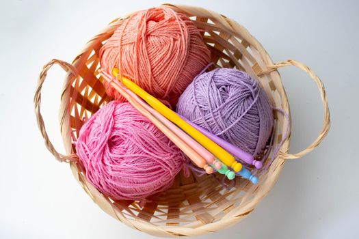 Balls of colored yarn in a basket on white background.