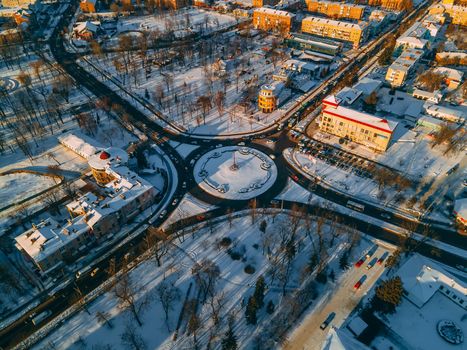 Aerial view of roundabout road with circular cars in small european city at winter sunset