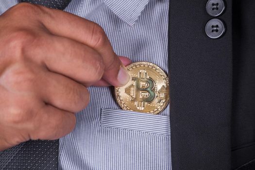 business man in suit pick bitcoin in to pocket